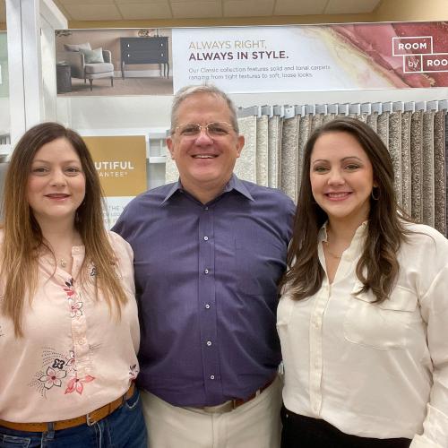 two women and man smiling in flooring store.